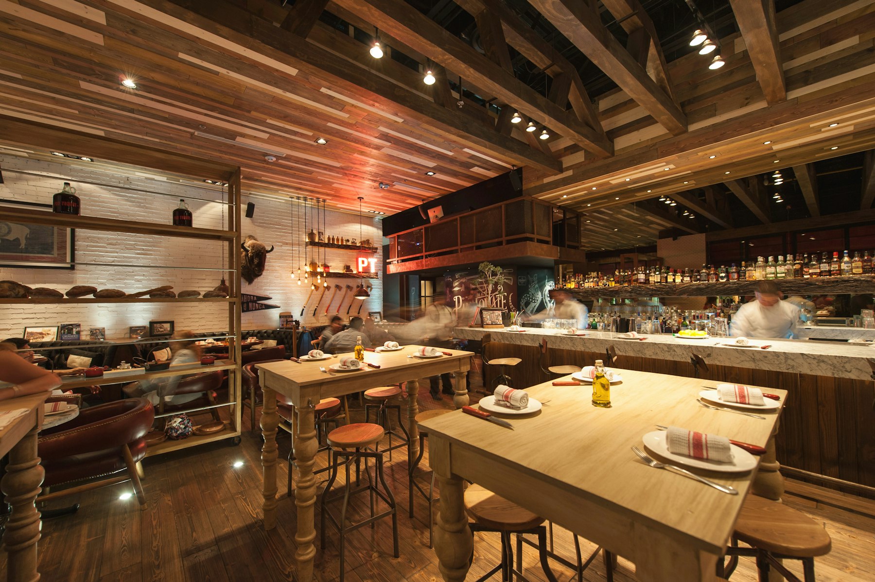 Sala restaurantului, cu mese de lemn și bucătărie deschisă