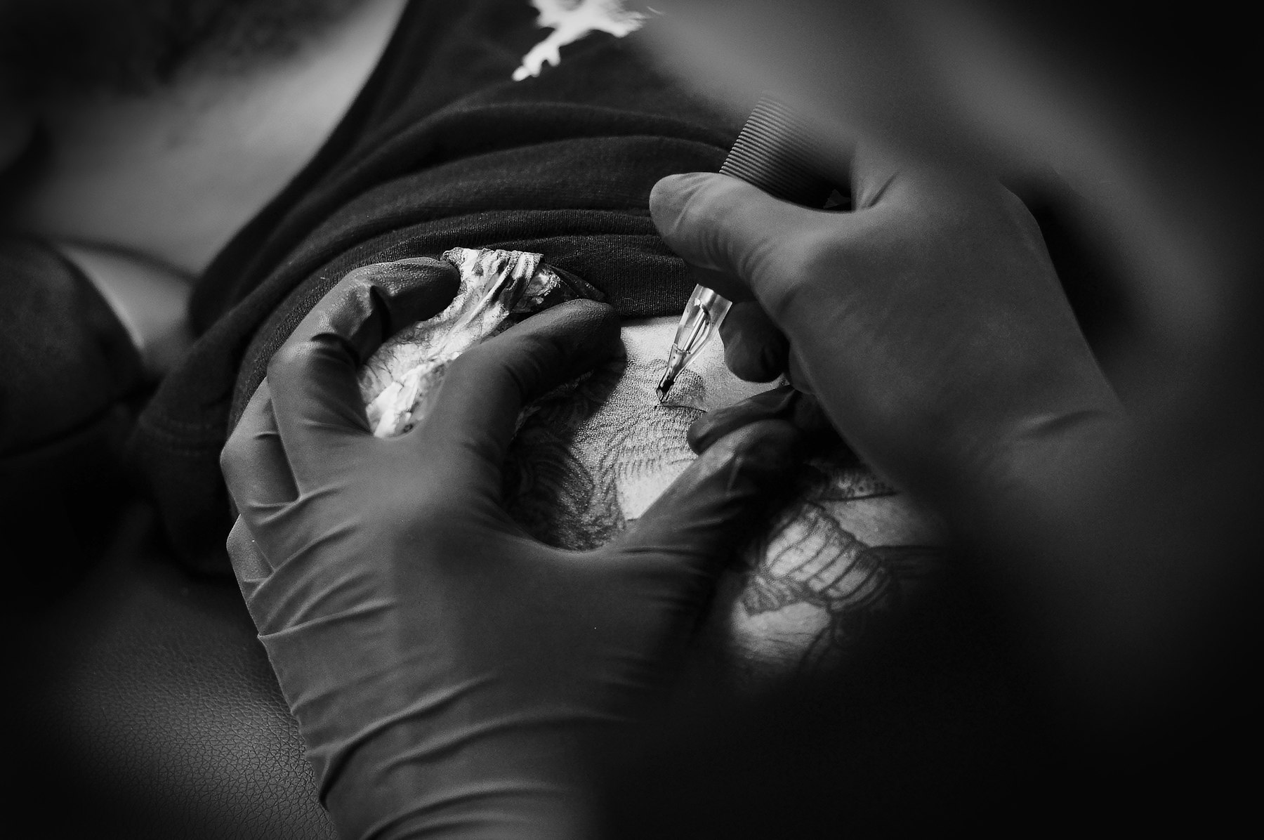 Detaliu în timpul tatuării, cu mănuși negre